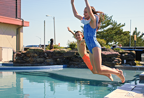 Kids jumping into the pool at ICONA Windrift resort hotel in Avalon