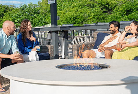 Friends sitting around a fire pit at the ICONA Windrift hotel in Avalon NJ