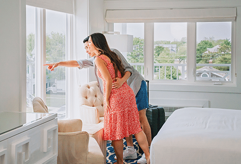 Couple pointing at the view outside the window of their ICONA Cape May hotel room