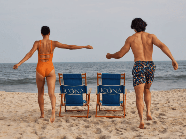 Couple running past ICONA beach chairs to the ocean