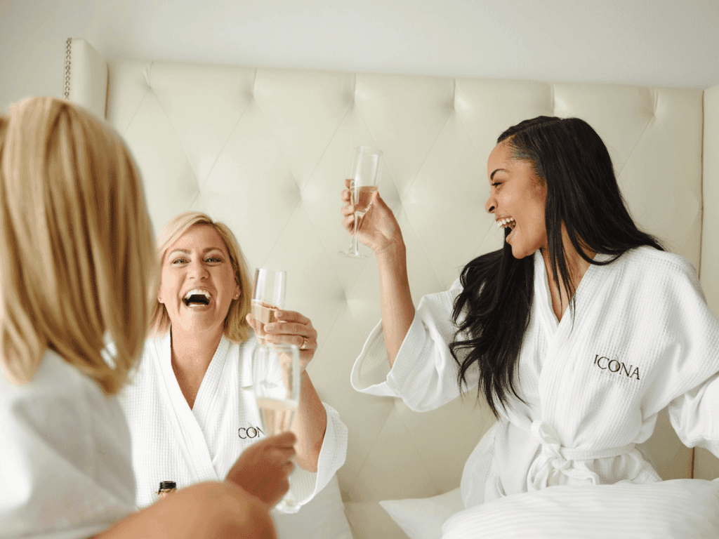 Friends in robes in bed on a girls weekend at ICONA Resorts