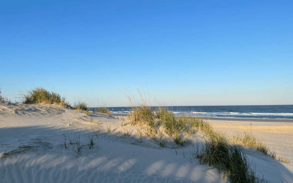 beautiful view of avalon nj beach at ICONA resort with sand dune, ocean waves, and blue skies