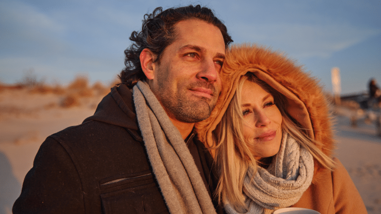 Couple looking at the sunrise on the beach during a cozy beach getaway