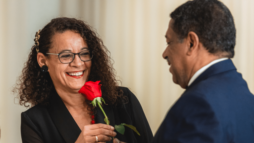 Wife smiling as her husband hands her a rose