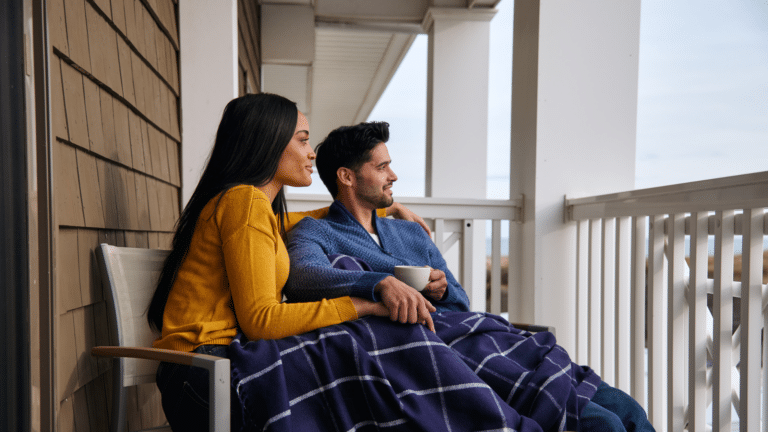 Couple sitting on the balcony at ICONA Avalon looking out at the ocean